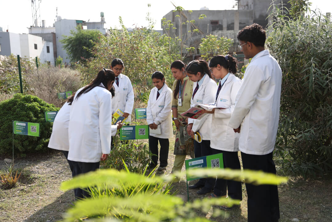 Ayurveda students identifying medicinal plants with QR labels in the UMCAR Herbal Garden